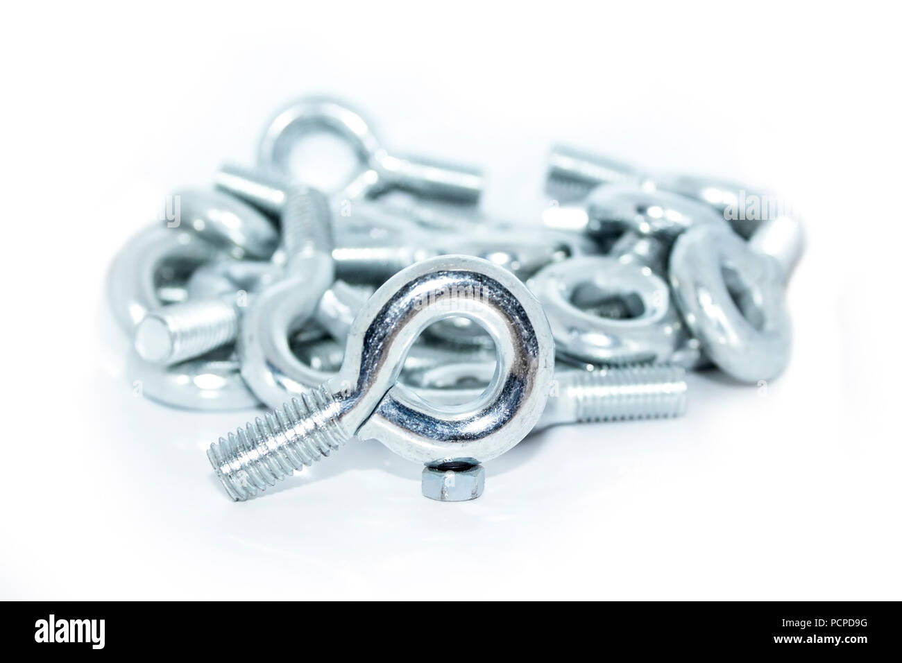 Lots of big industrial galvanized eye bolts on a pile with white background Stock Photo