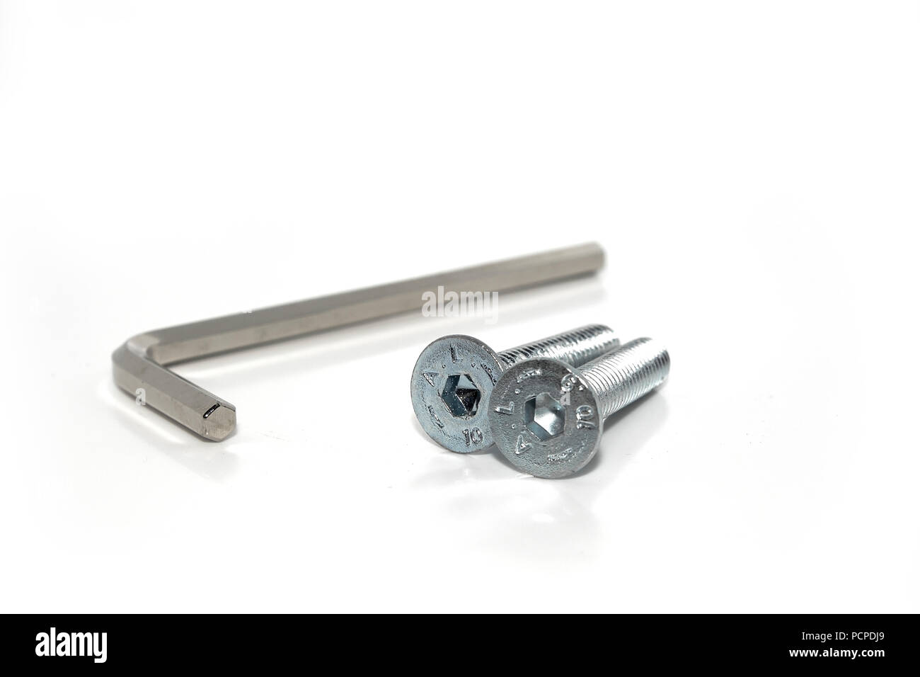 Single isolated Allen screw driver wrench with a couple of screws on white background Stock