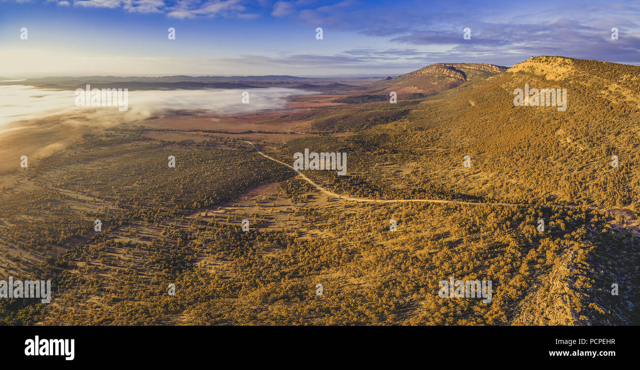 Aerial panorama of winding dirt road in Flinders Ranges hills at sunrise. Hawker, South Australia Stock Photo