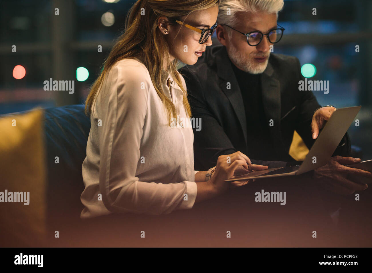 Businesswoman with her boss sitting in office and working on laptop. Two business people working late in office with finish a project. Stock Photo