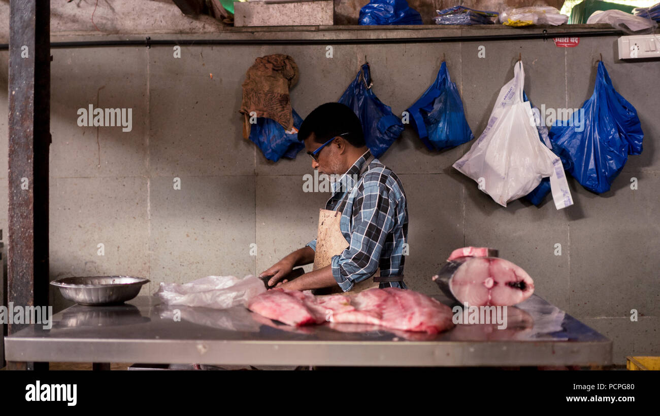 A fishmonger cuts fish at the Shivaji Market, Pune Stock Photo