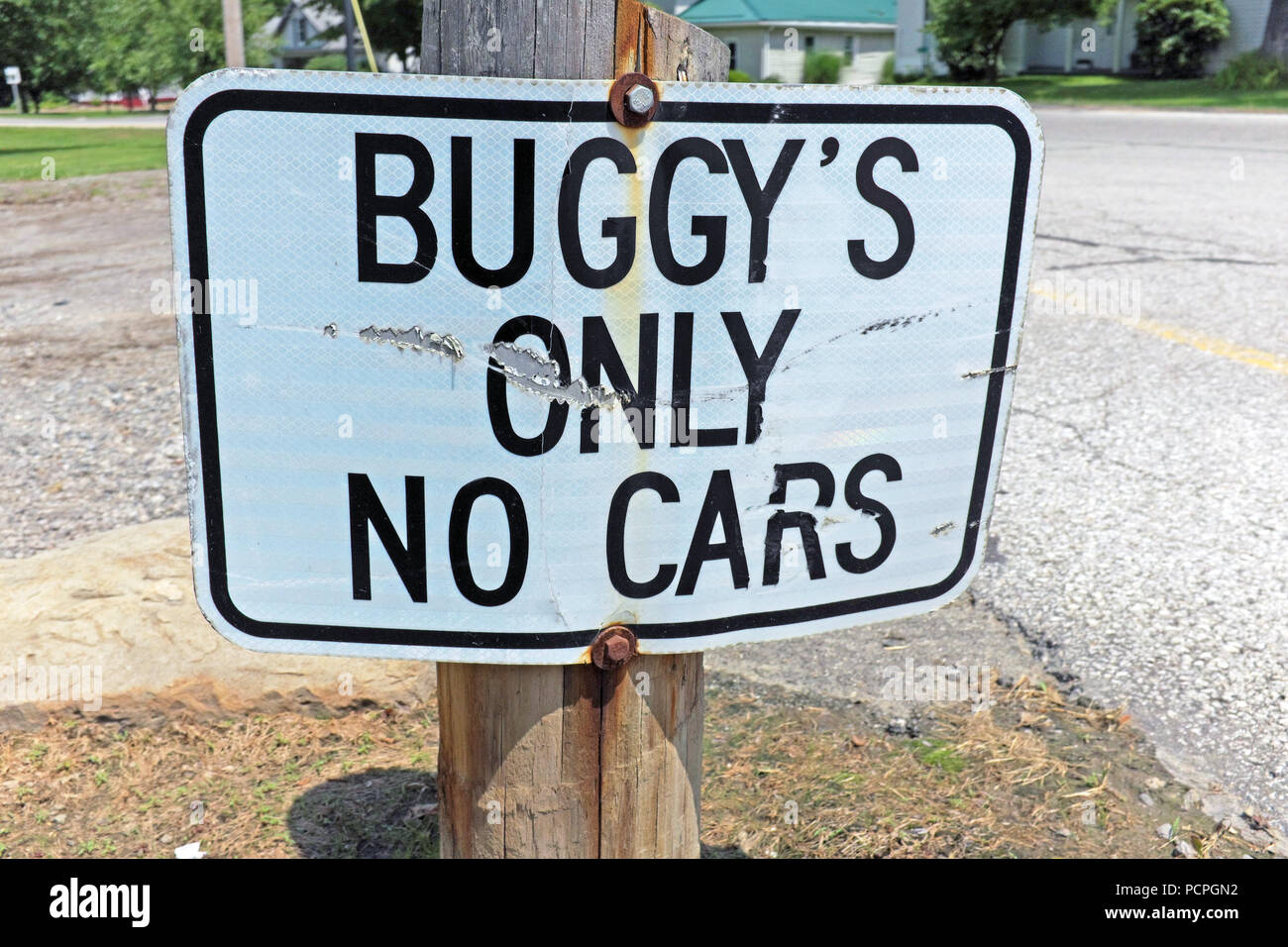 'Buggy's Only No Cars' metal sign is posted near ground level in a horse-carriage parking area in the Mesopotamia Township Amish community commons. Stock Photo