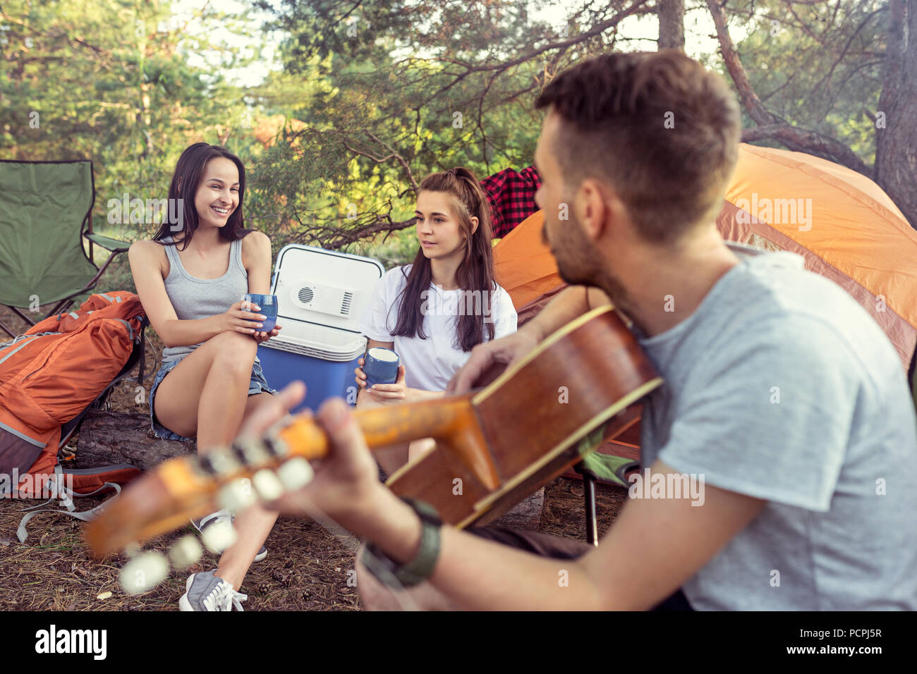 Party, camping of men and women group at forest. They relaxing, singing