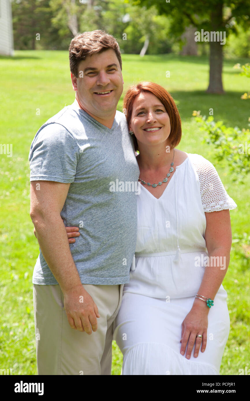 A happily married man and woman pose for a photo on a sunny day outside ...