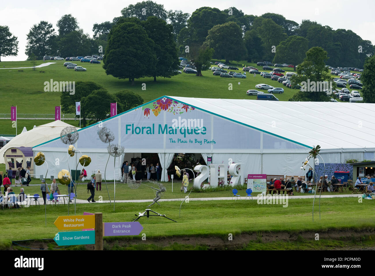 Showground at RHS Chatsworth Flower Show (people visiting, large floral marquee, giant sculptural flowers & hillside car park) Derbyshire, England, UK Stock Photo