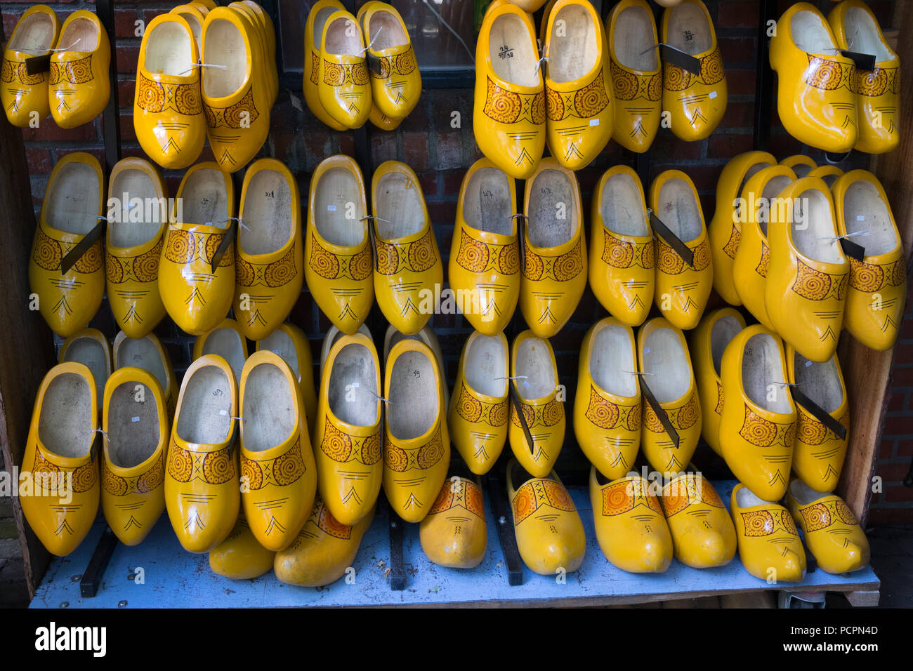 Pairs of yellow wooden shoes in a shop hanging on a wall for sale Stock Photo