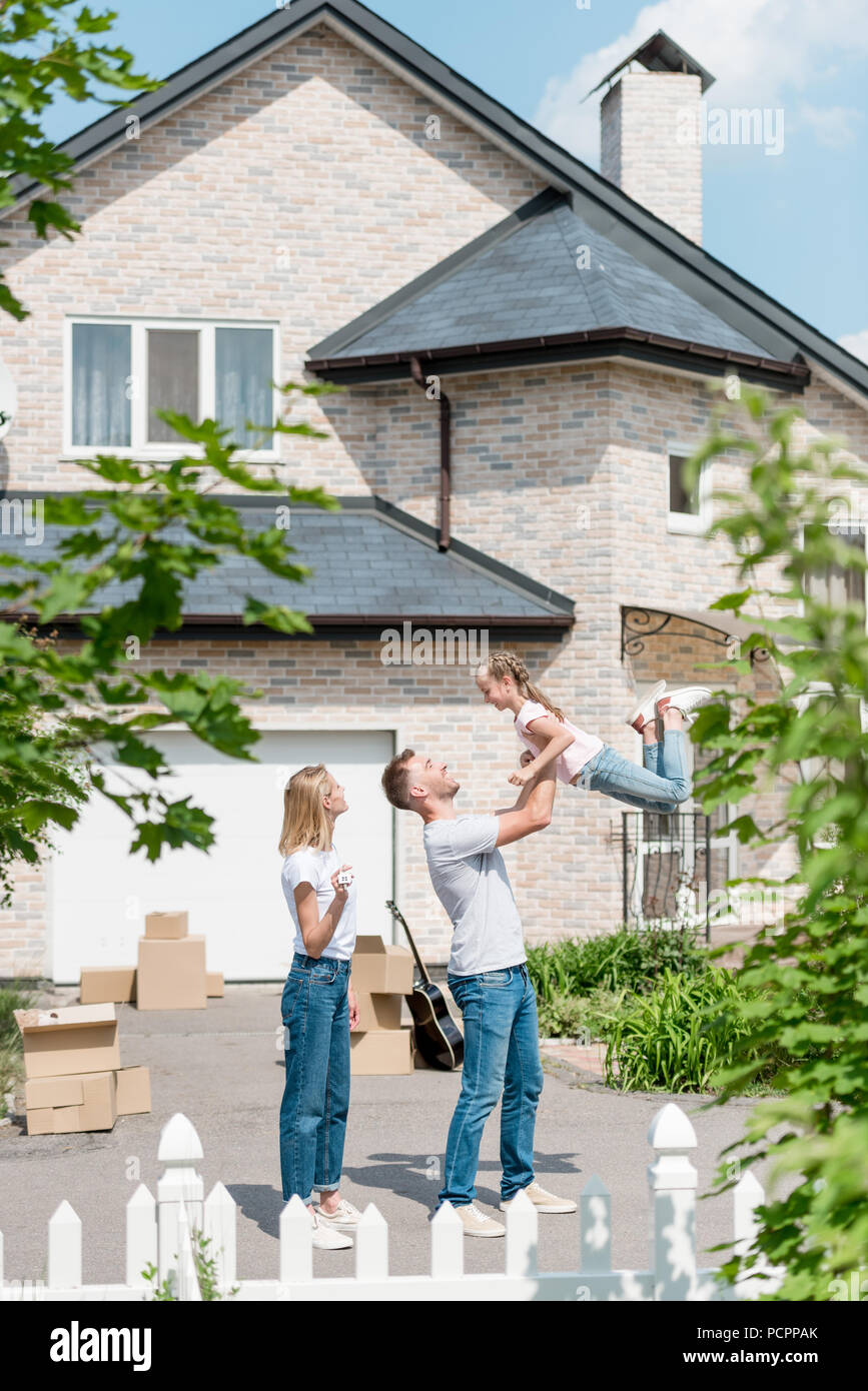 Side View Of Father Raising Up Daughter While Mother Standing Near