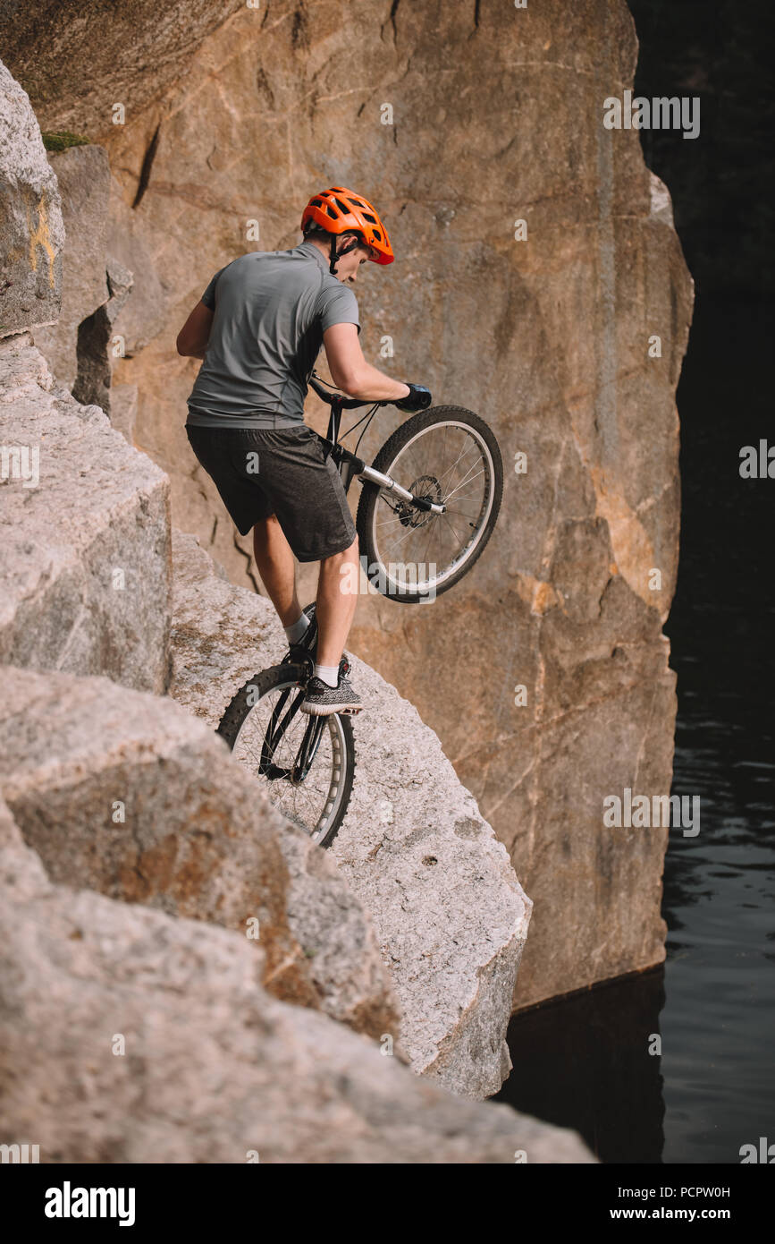 high angle view of trial biker balancing on back wheel on rocks outdoors Stock Photo