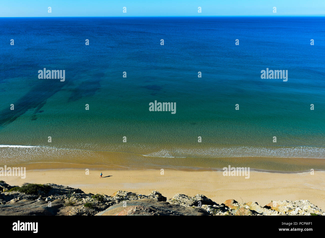 Lonely beach runner running on the sandy beach of Praia da Luz, Luz, Algarve, Portugal Stock Photo