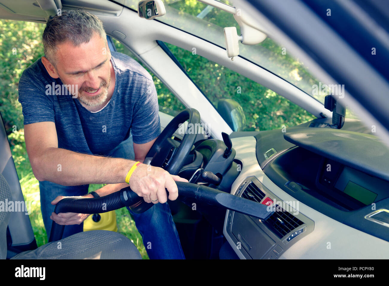 Man hoovering a air vents inside a car cabin, Stock Photo
