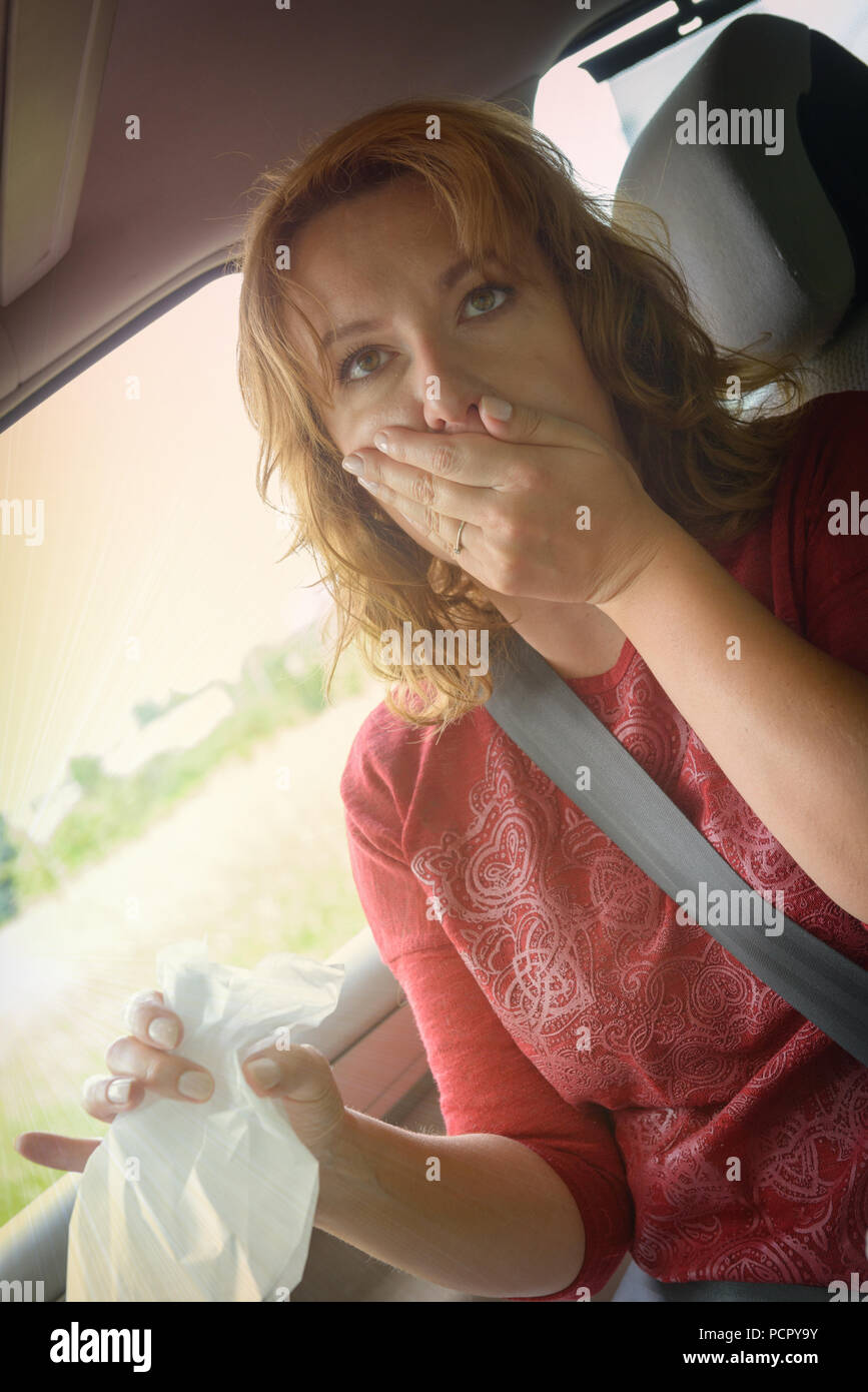 Woman suffering from motion sickness in a car and holding sick bag