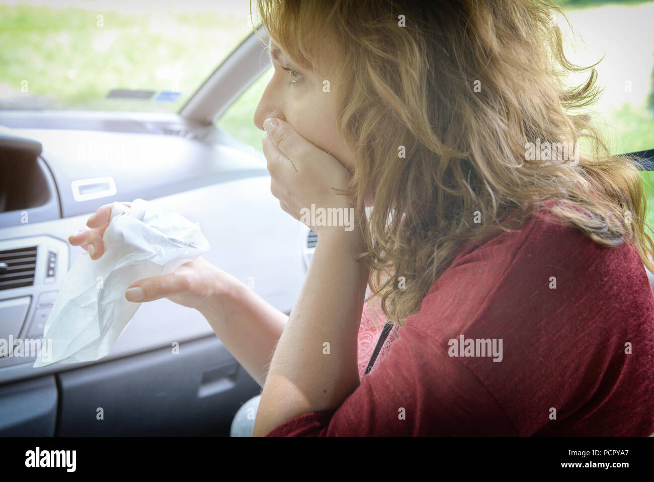 Woman suffering from motion sickness in a car and holding sick bag