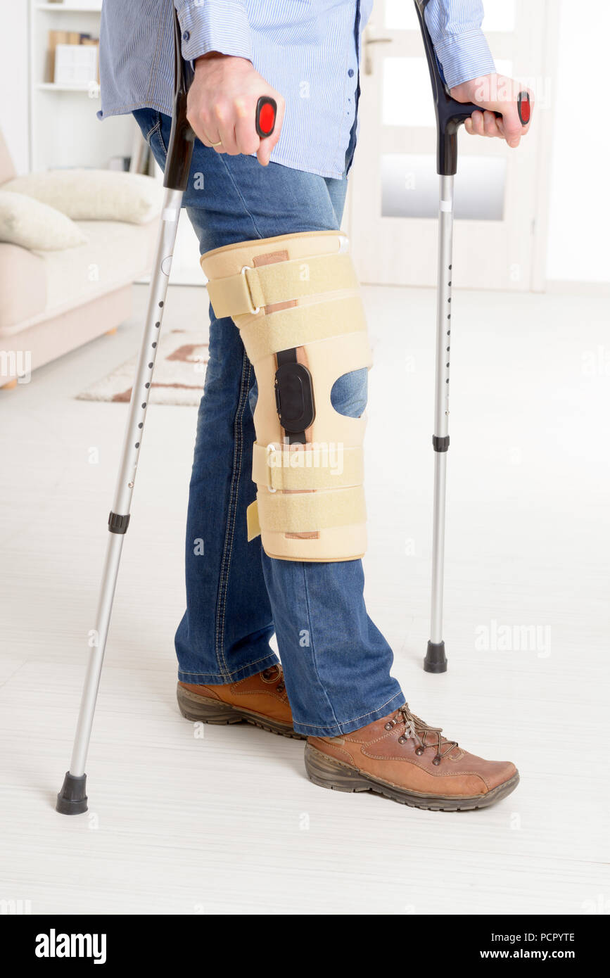 Man with leg in knee cages and crutches for stabilization and support