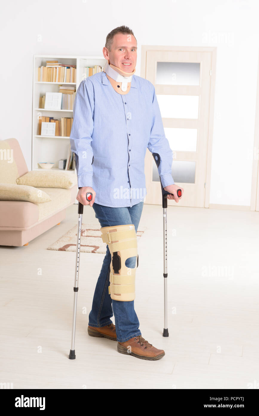 Man with leg in neck brace, knee cages and crutches for stabilization and  support Stock Photo - Alamy