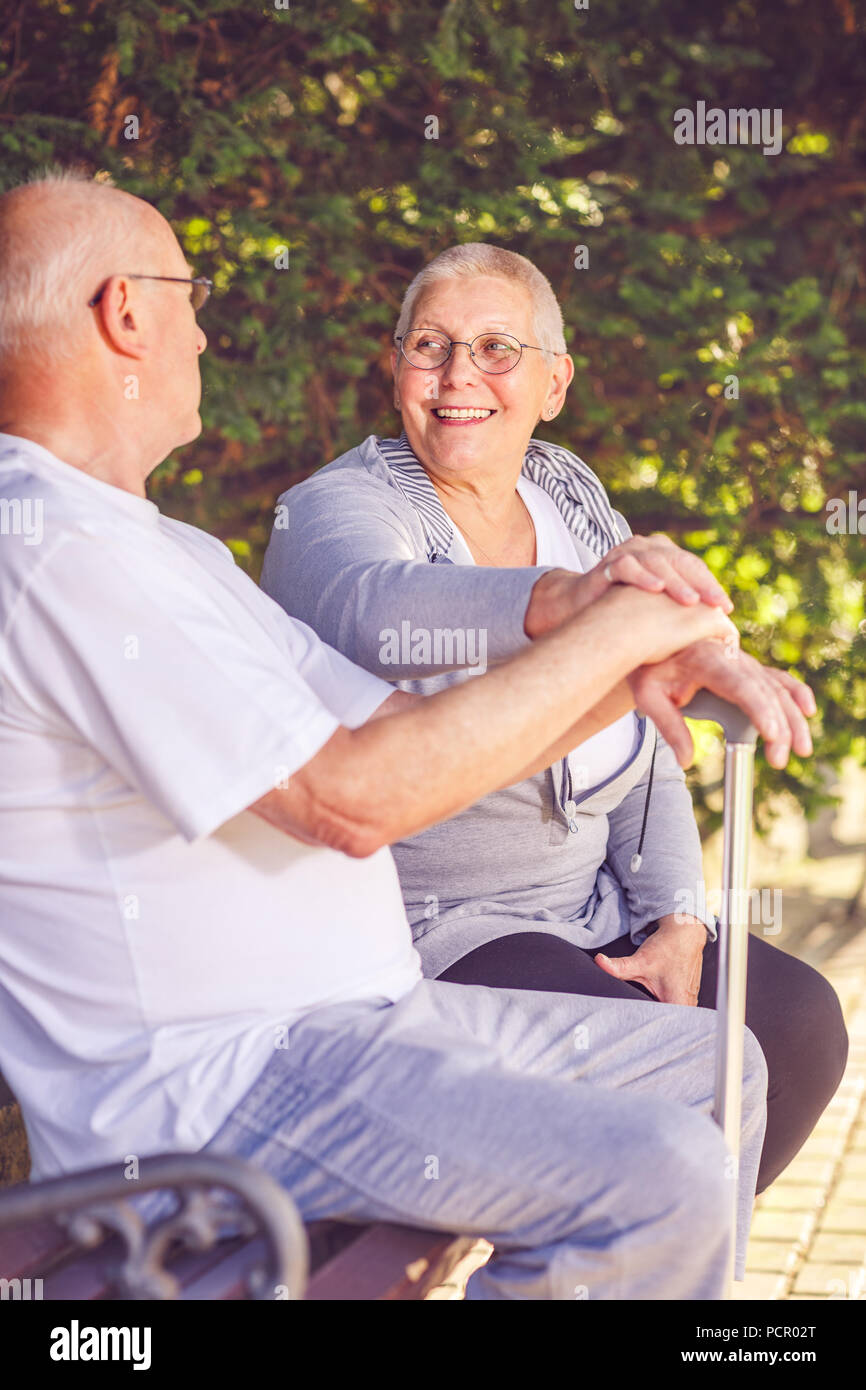 Relaxed pensioner couple sitting on a park bench Stock Photo