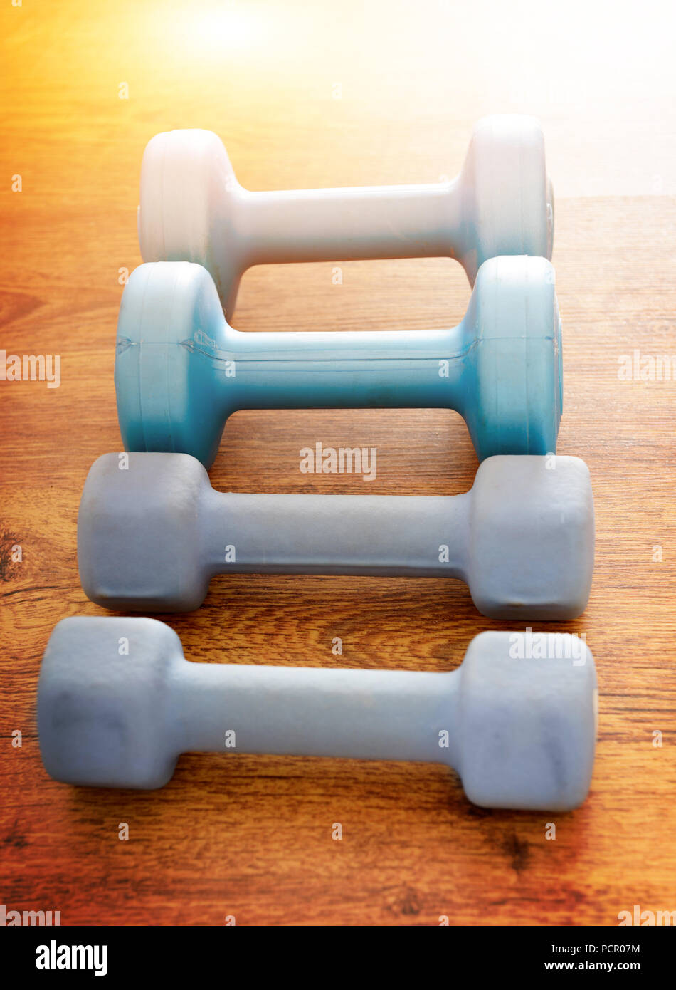 Blue dumb-bells  over wooden gym's floor Stock Photo