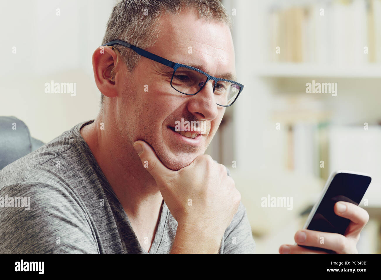 Hearing impaired man with hearing aid using smart phone at home or at office Stock Photo Alamy