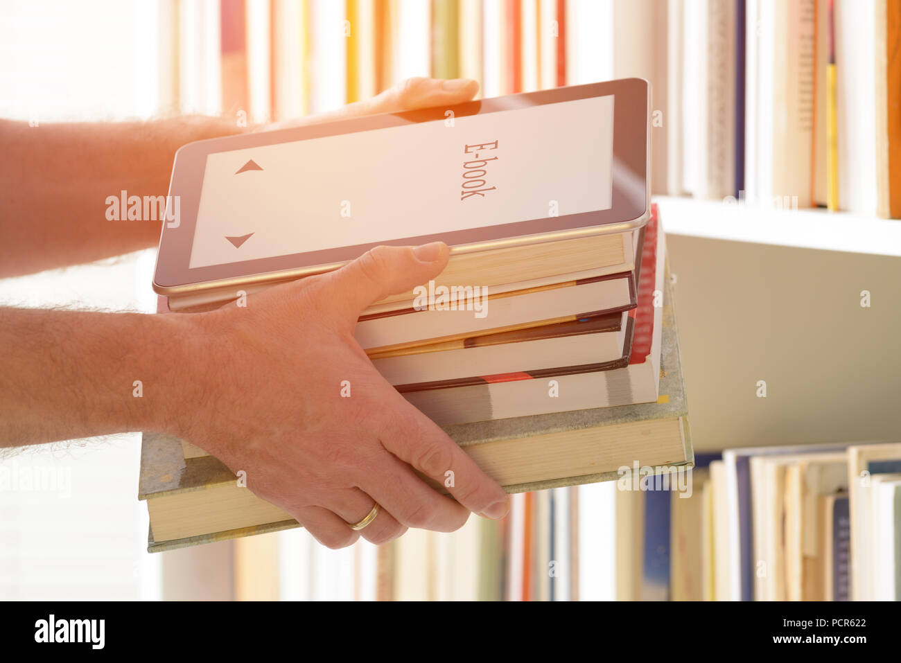 Man holding in hands a modern ebook reader and paper books, bookshelf