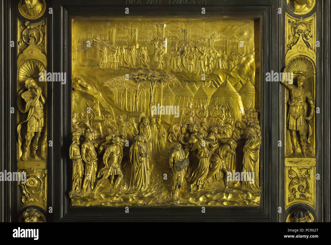 Story of Joshua depicted in the gilded bronze panel from the Gates of Paradise (Porta del Paradiso) designed by Italian Early Renaissance sculptor Lorenzo Ghiberti for the Florence Baptistery (Battistero di San Giovanni), now on display in the Museo dell'Opera del Duomo (Museum of the Works of the Florence Cathedral) in Florence, Tuscany, Italy. The Israelites cross the Jordan River (bellow) and the Battle of Jericho (above) are depicted in the panel. Stock Photo