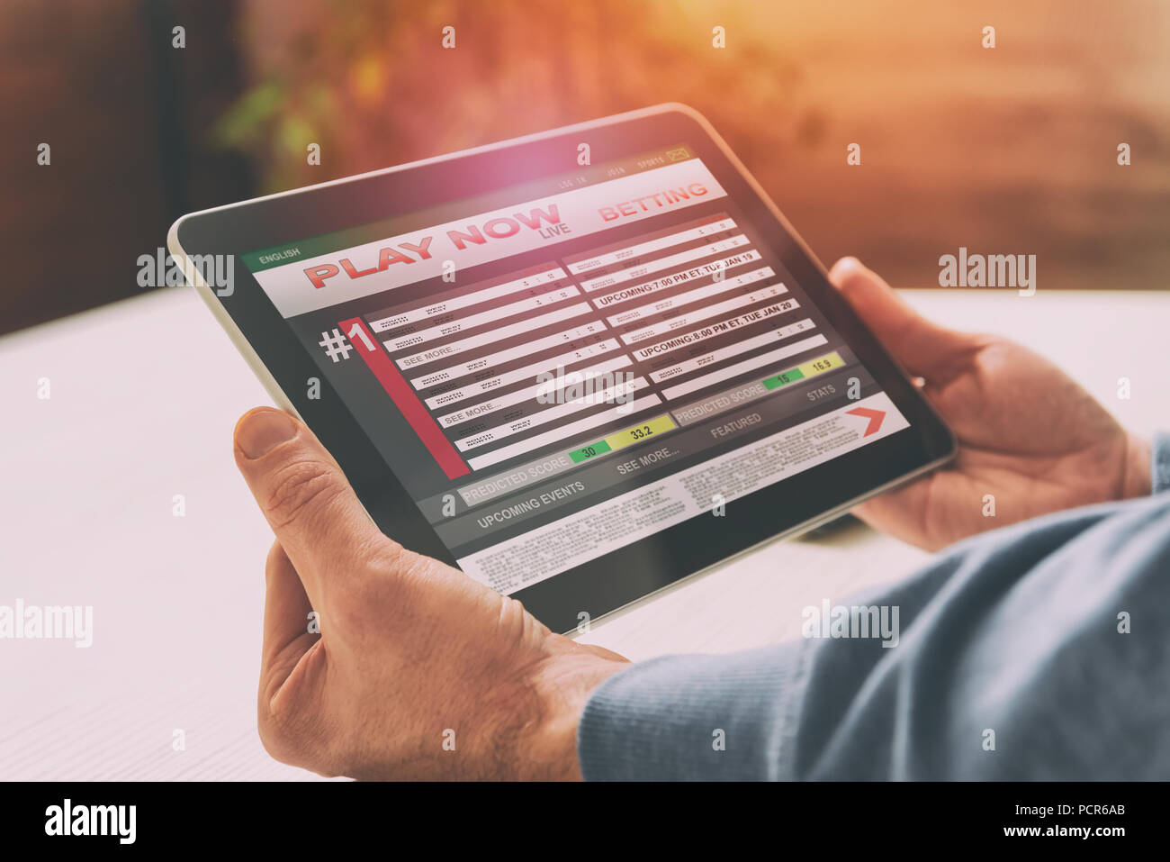 Man betting on sports, over shoulder view on tablet with scores Stock Photo