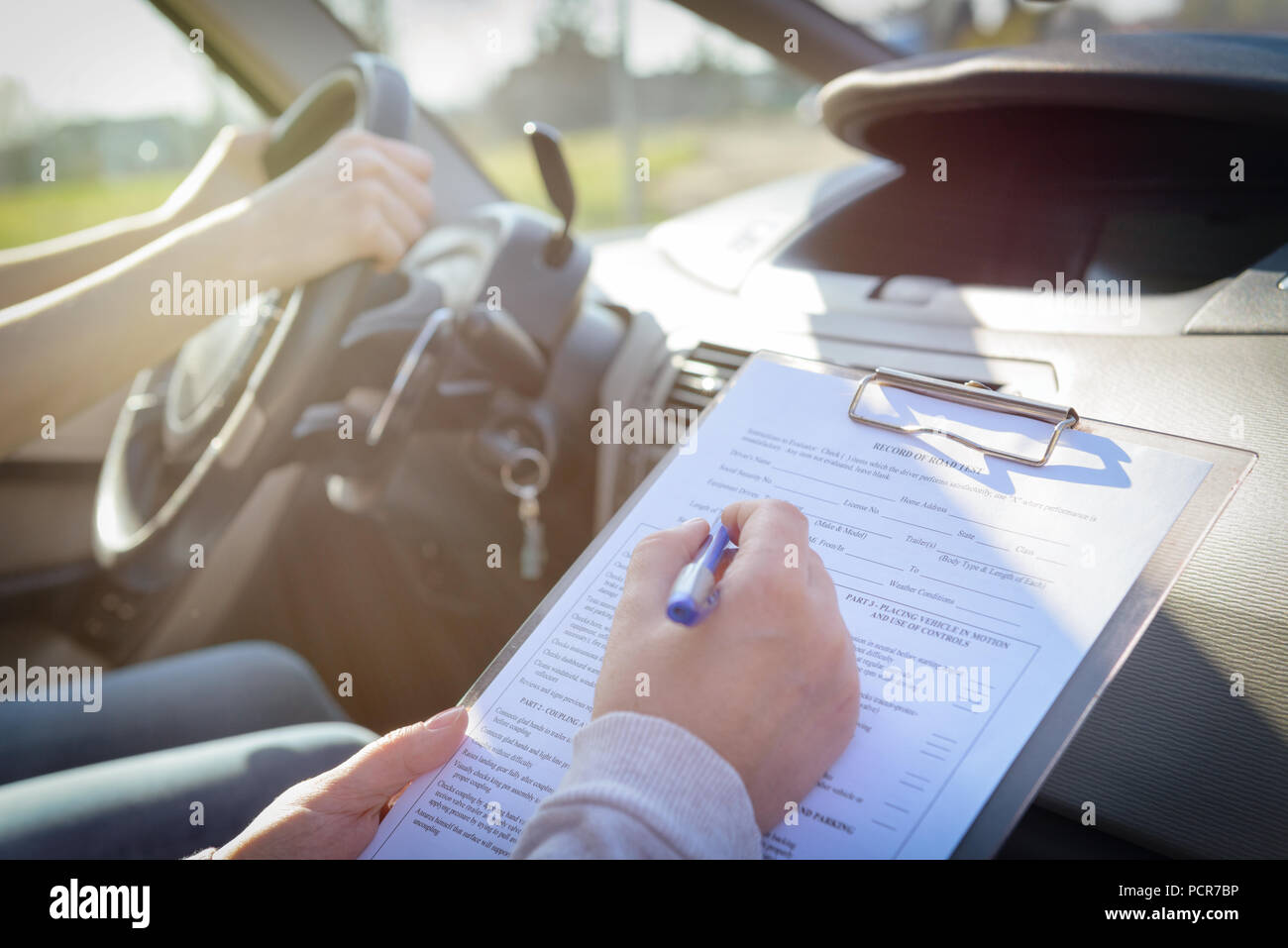 Driving Test Signing Box Examiner filling in driver's license road test form sitting with her ...