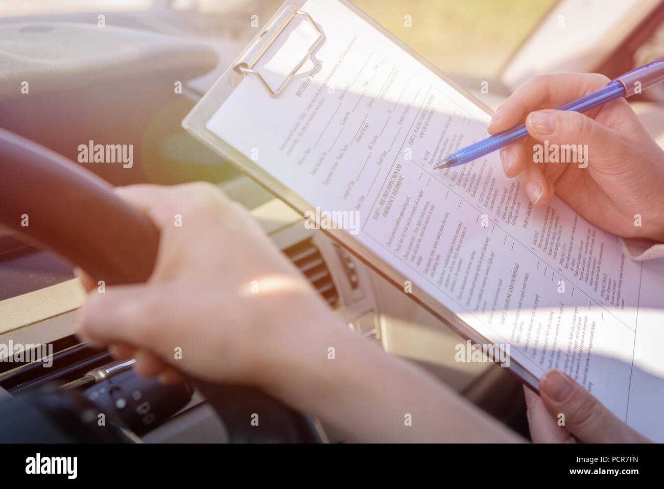 Examiner filling in driver's license road test form sitting with her ...