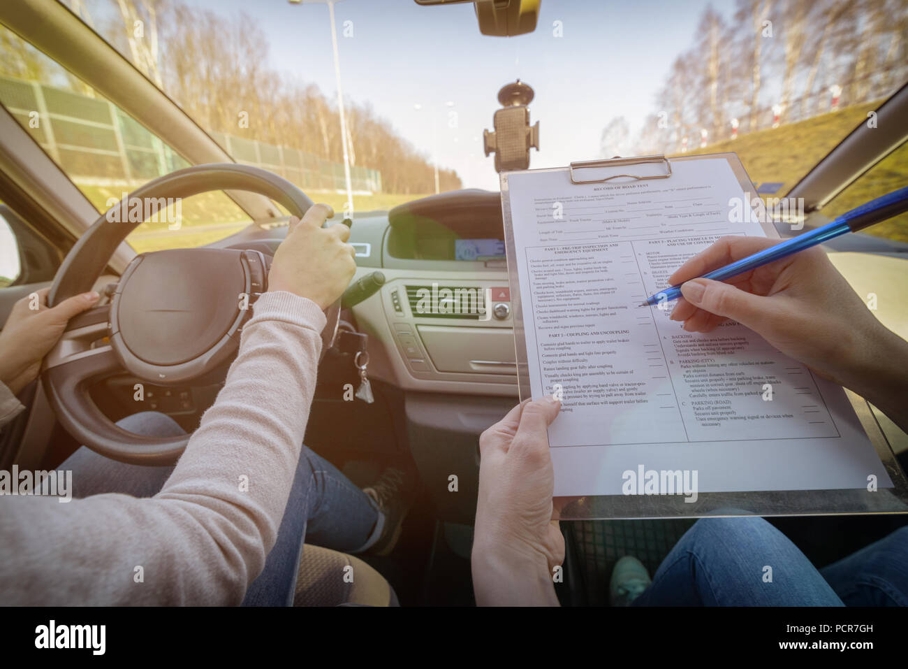 Examiner filling in driver's license road test form sitting with her ...