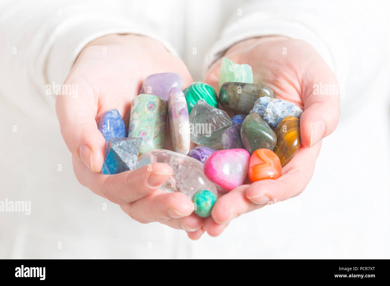 Multiple semi precious gemstones in hands Stock Photo