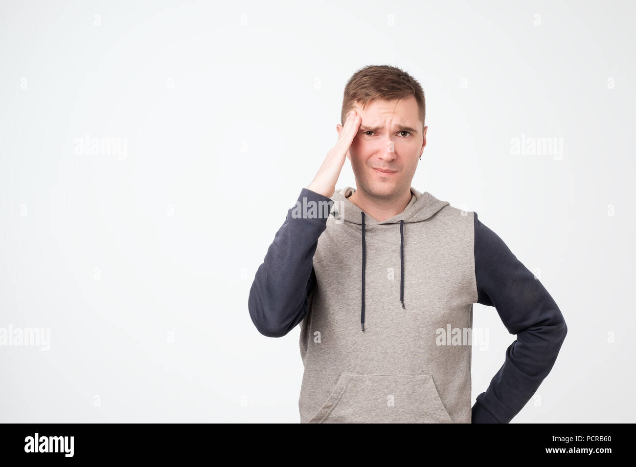 Upset unhappy european man student squeezing head with hands, writhing in pain, suffering from headache. People, stress, tension and migraine Stock Photo