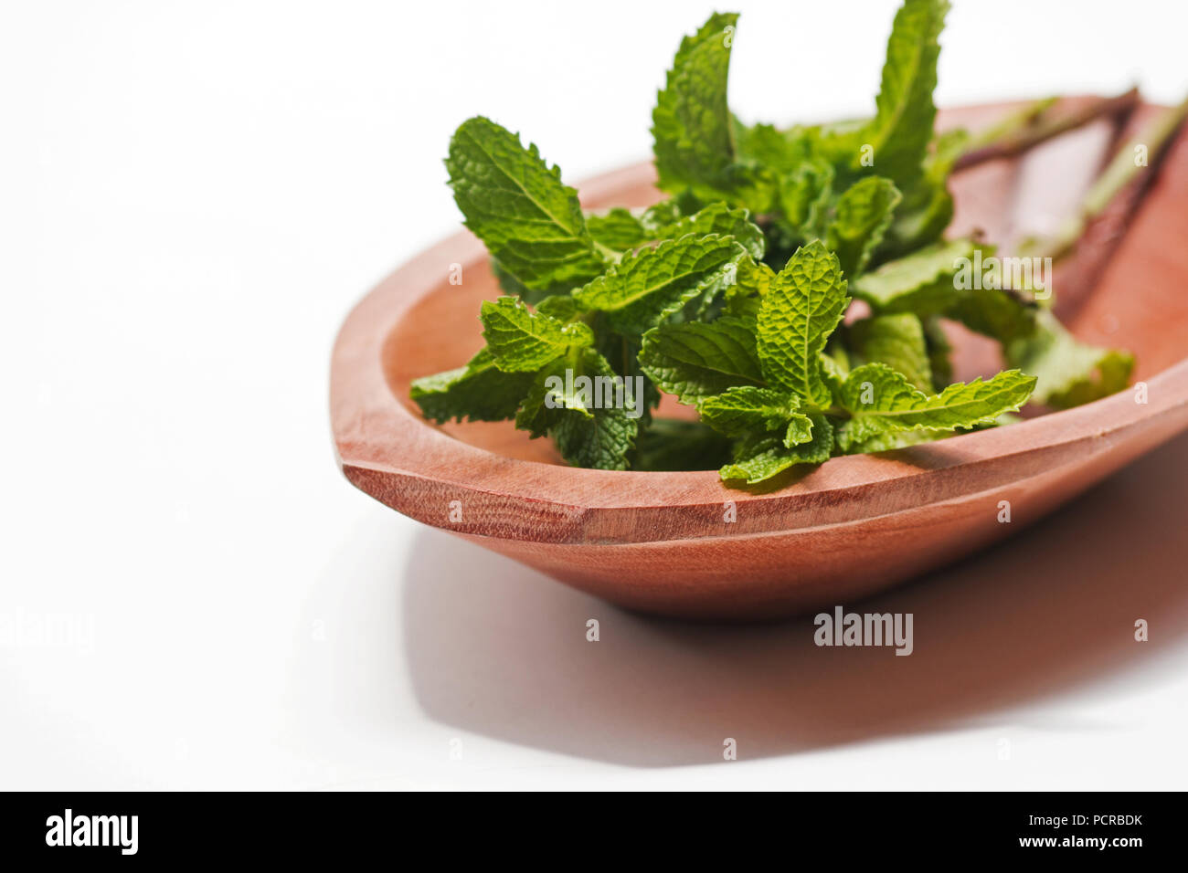 Mint cuttings in a wooden bowl on white background Stock Photo