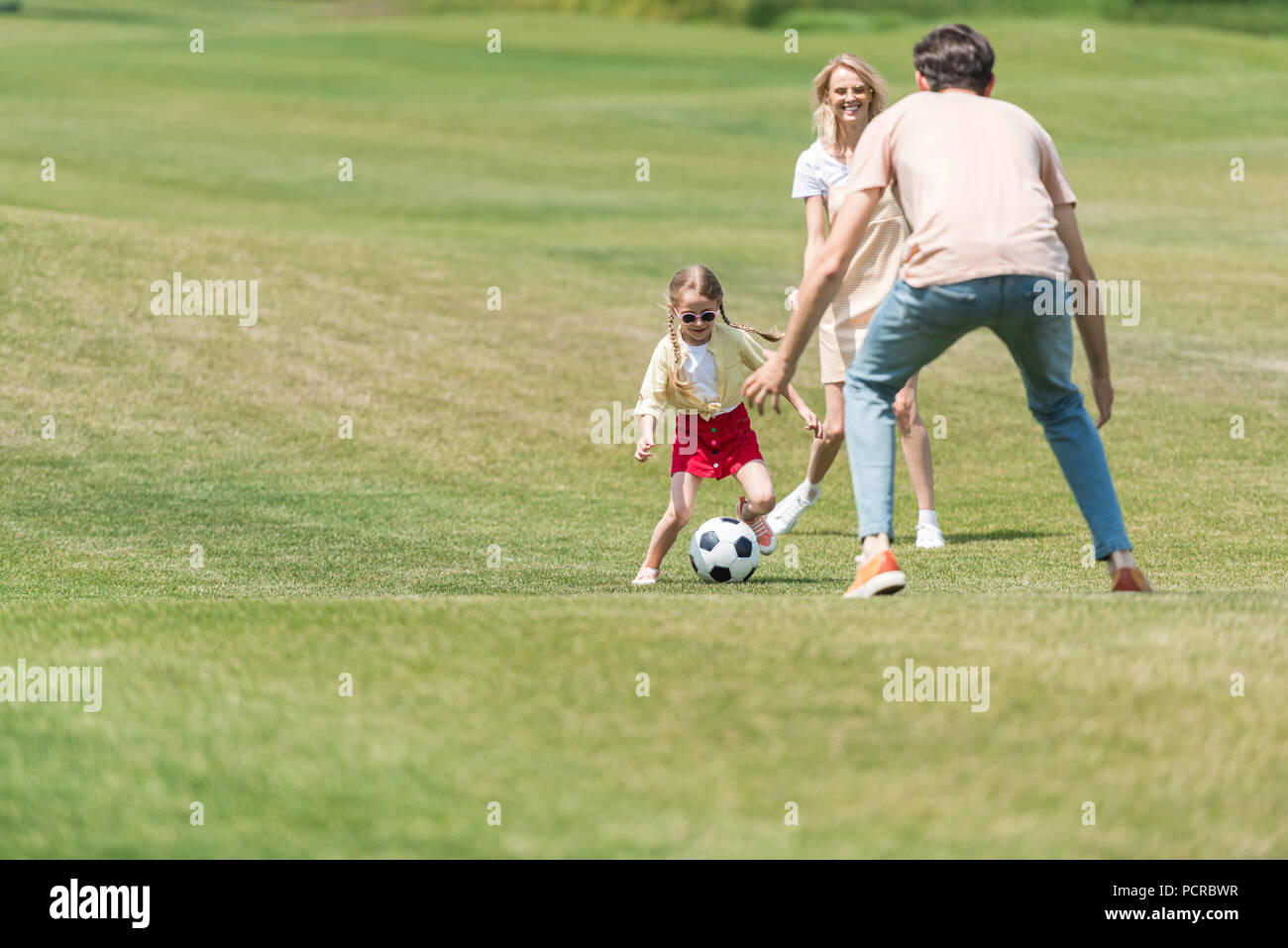 happy family with one child playing with soccer ball in park Stock ...