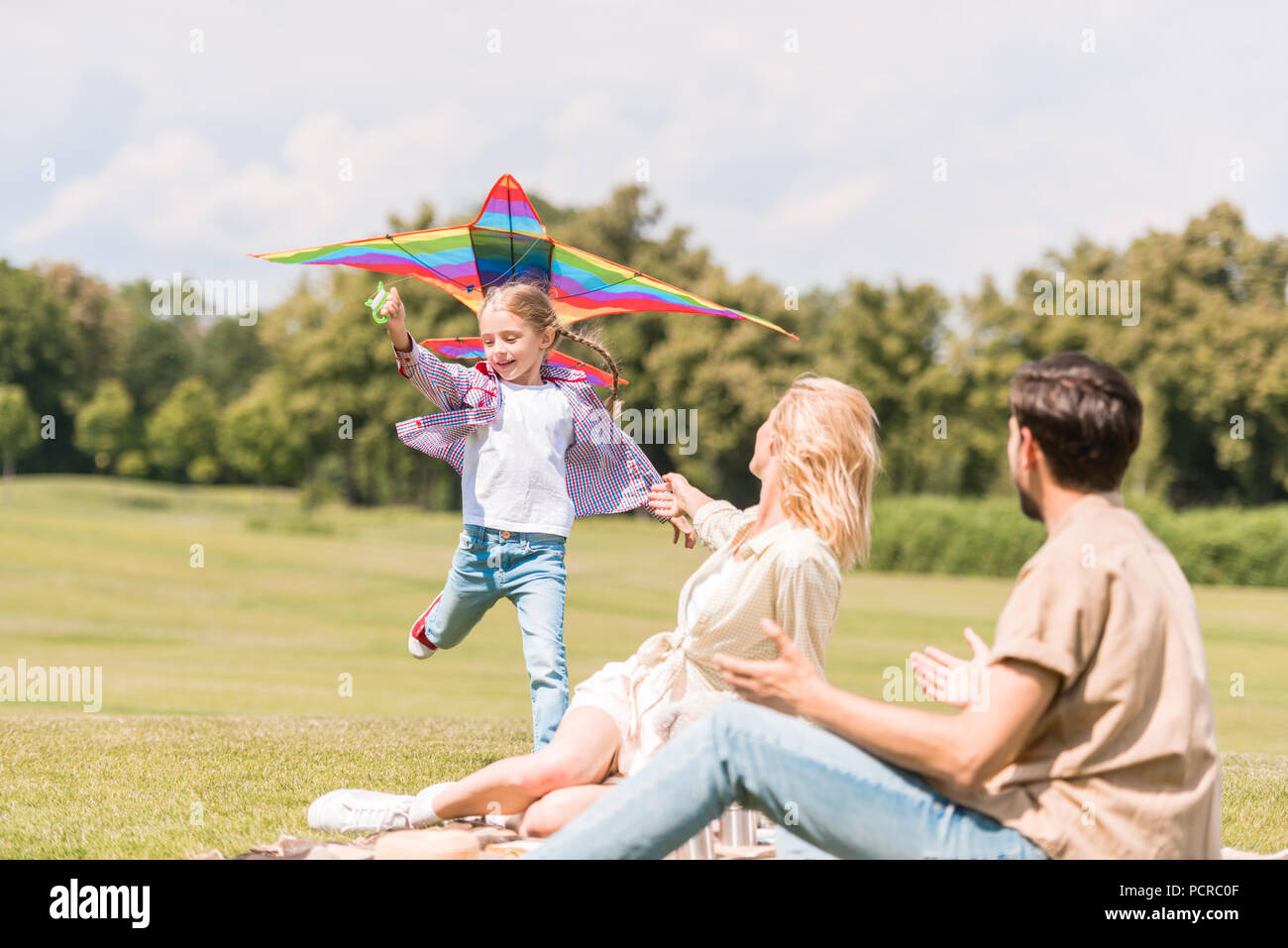 happy family with one child playing with colorful kite in park Stock ...