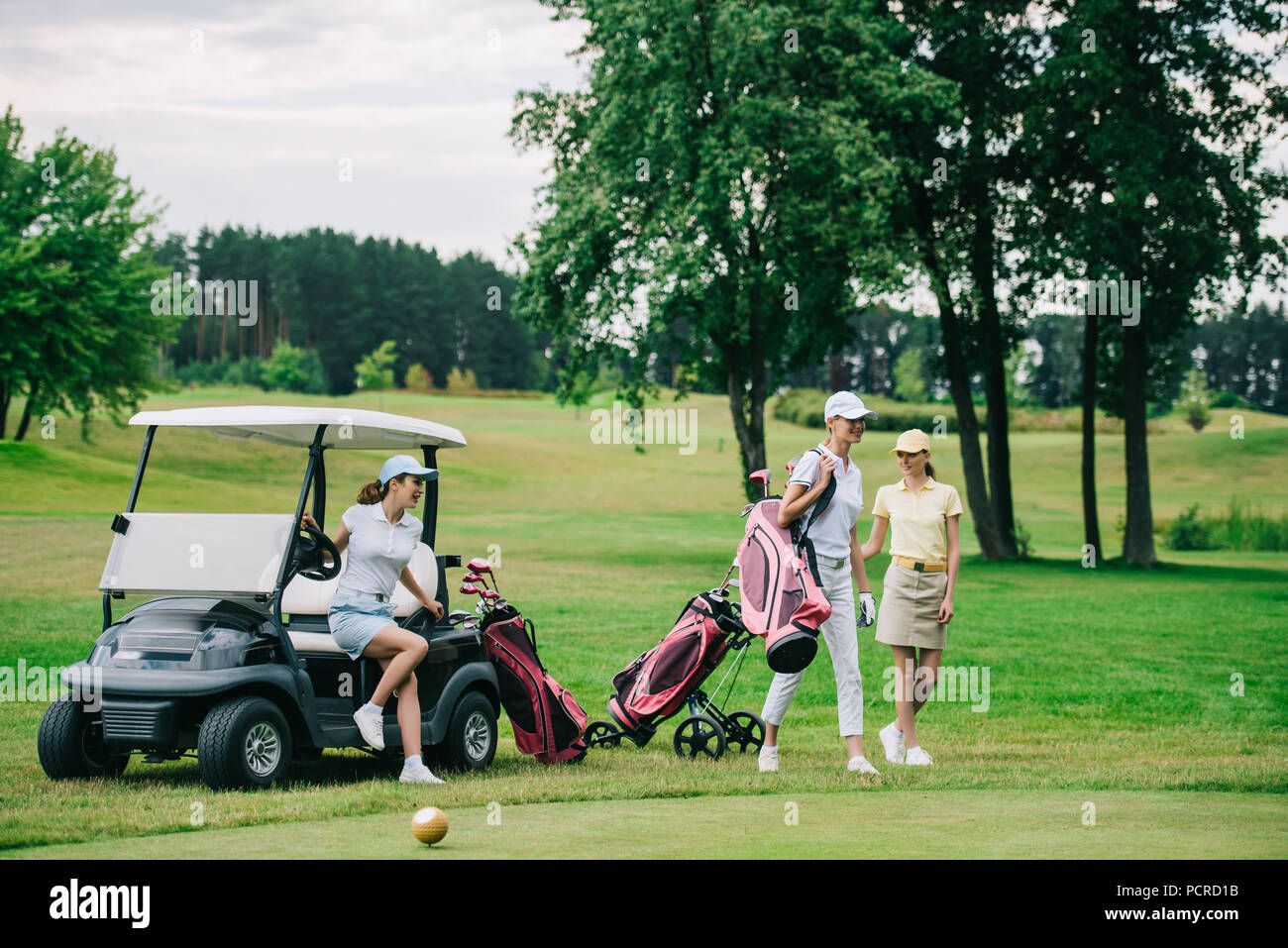 group of female golf players in caps with golf equipment at golf course