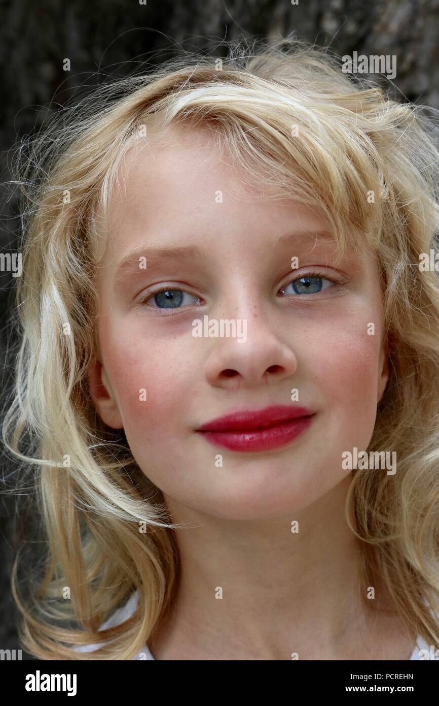 Portrait of a blonde young girl with bright red lipstickand a mysterious smile Stock Photo