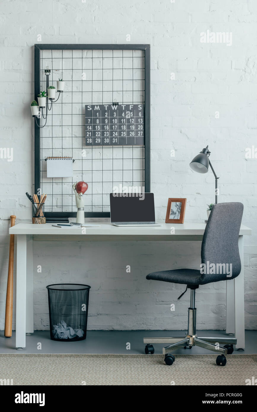 Laptop with blank screen on table in modern light office Stock Photo ...