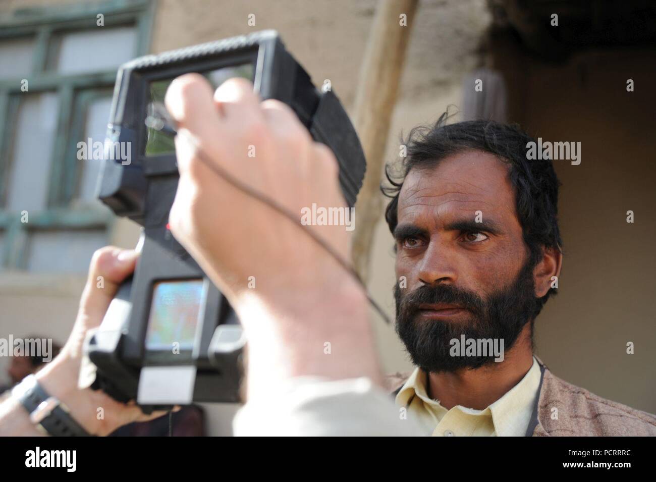 A coalition Special Operations Force member uses a biometric scanner on a villager in Sayadabad district, Wardak province.  Afghan National Army Commandos, assisted by coalition SOF, led a multi-day clearing operation and conducted a unilateral patrol in Saydabad. Stock Photo
