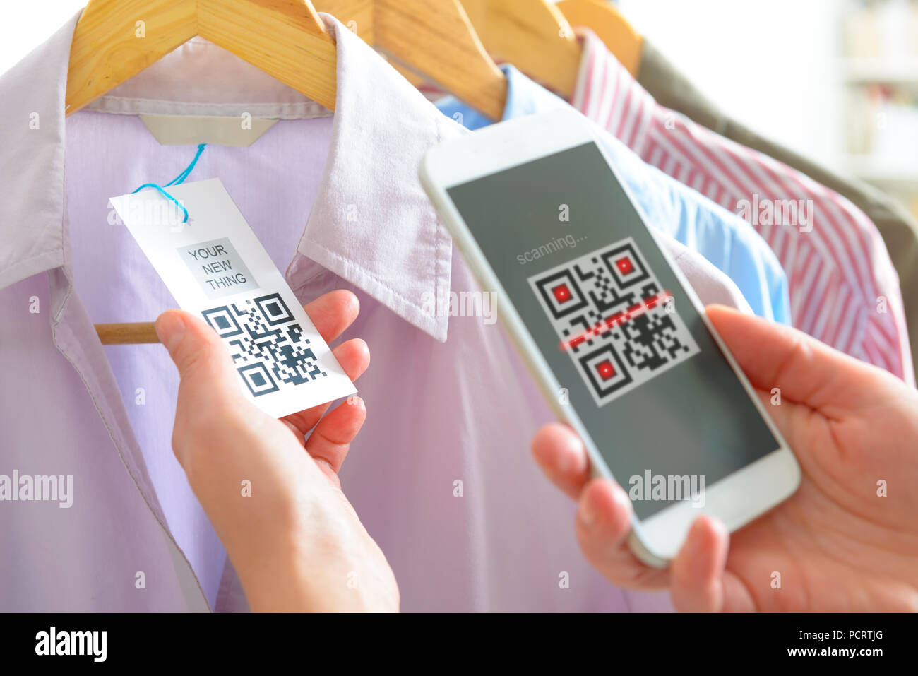 Woman scanning QR code from a label in a shop with mobile phone Stock