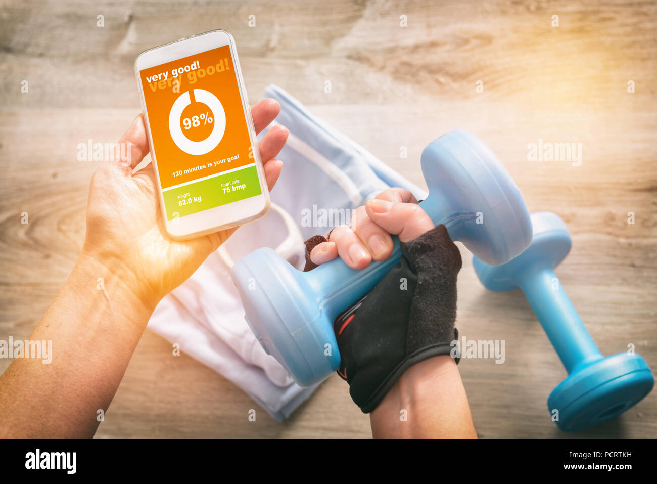 Mobile phone with sport mobile application on screen dumbbels and other sport equipment on a desk Stock Photo