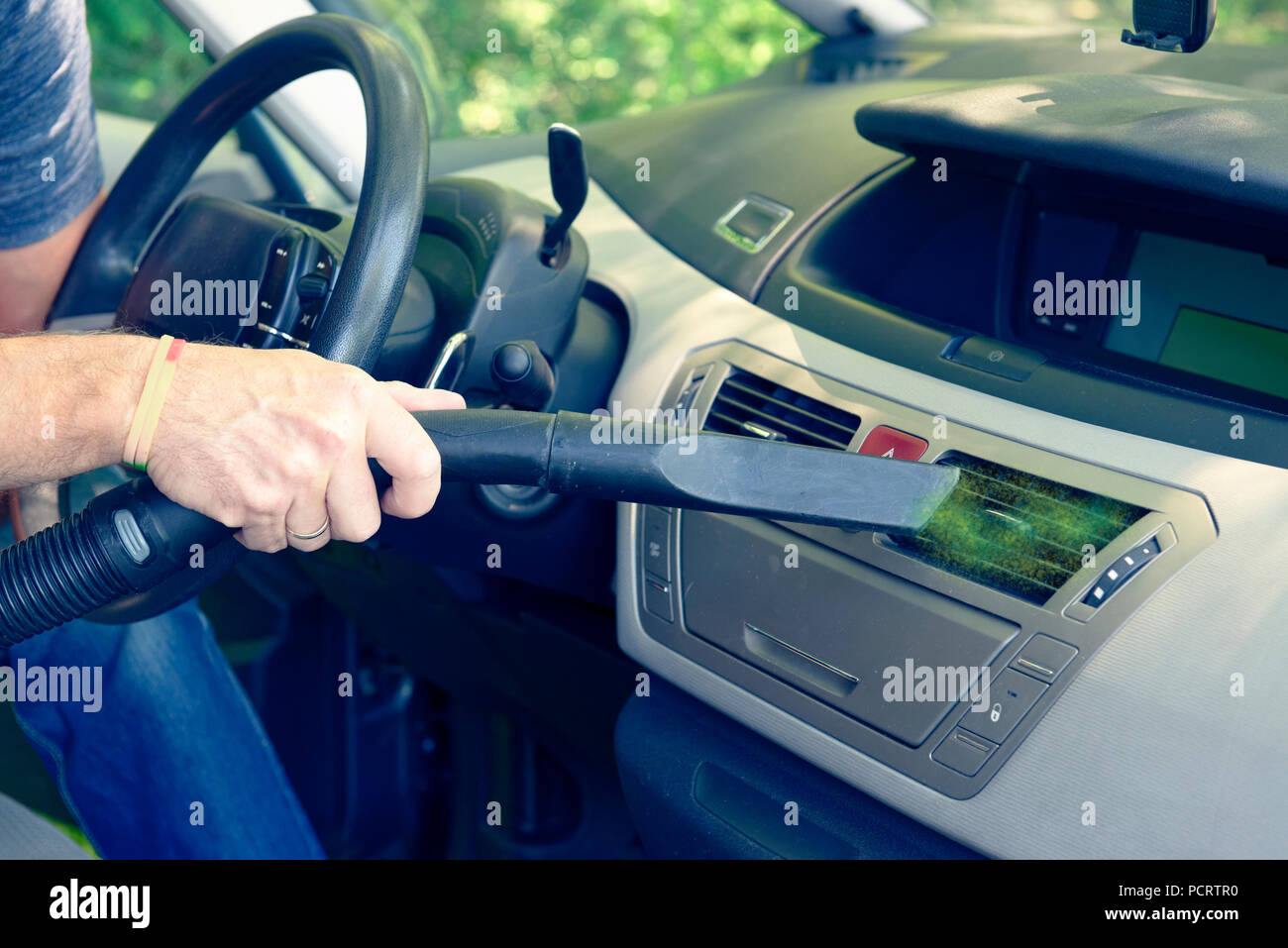 Man hoovering a air vents inside a car cabin. Using vacuum cleaner