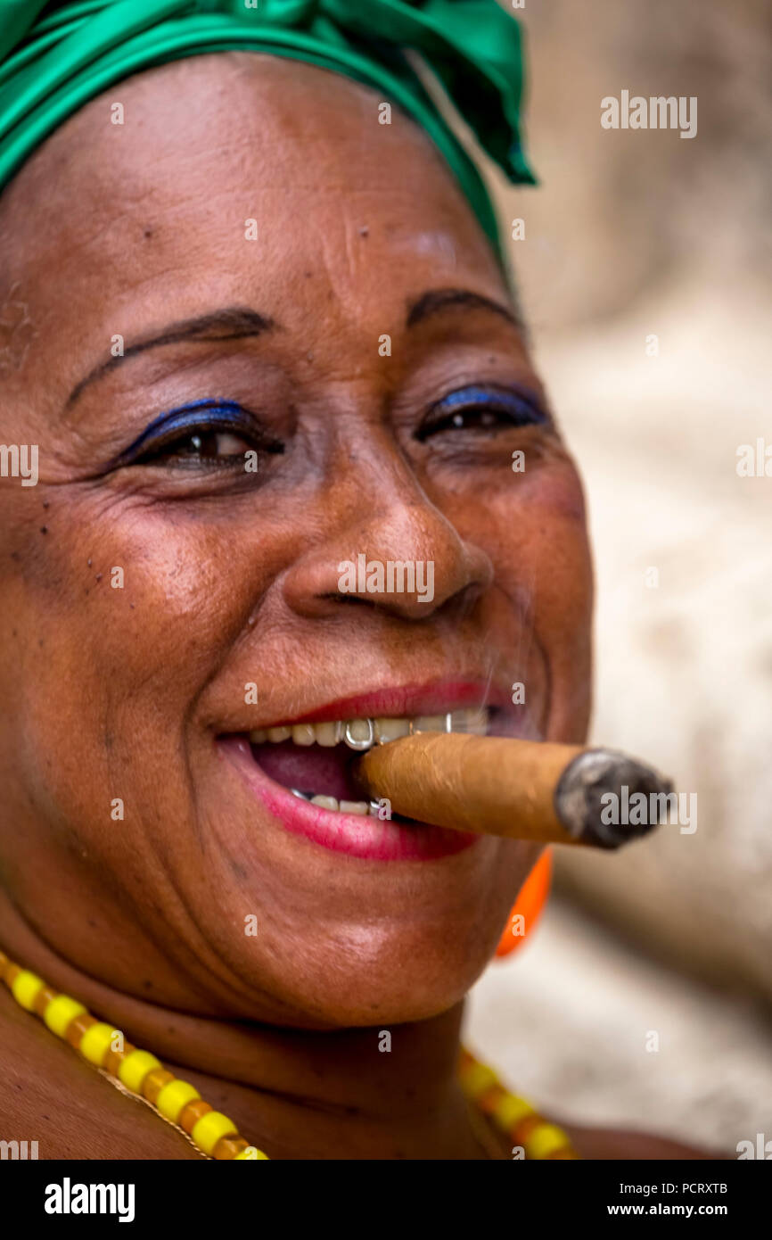 old Cuban woman with green hair ribbon smokes a Havana cigar, Caribbean, Central America, La Habana, Cuba Stock Photo