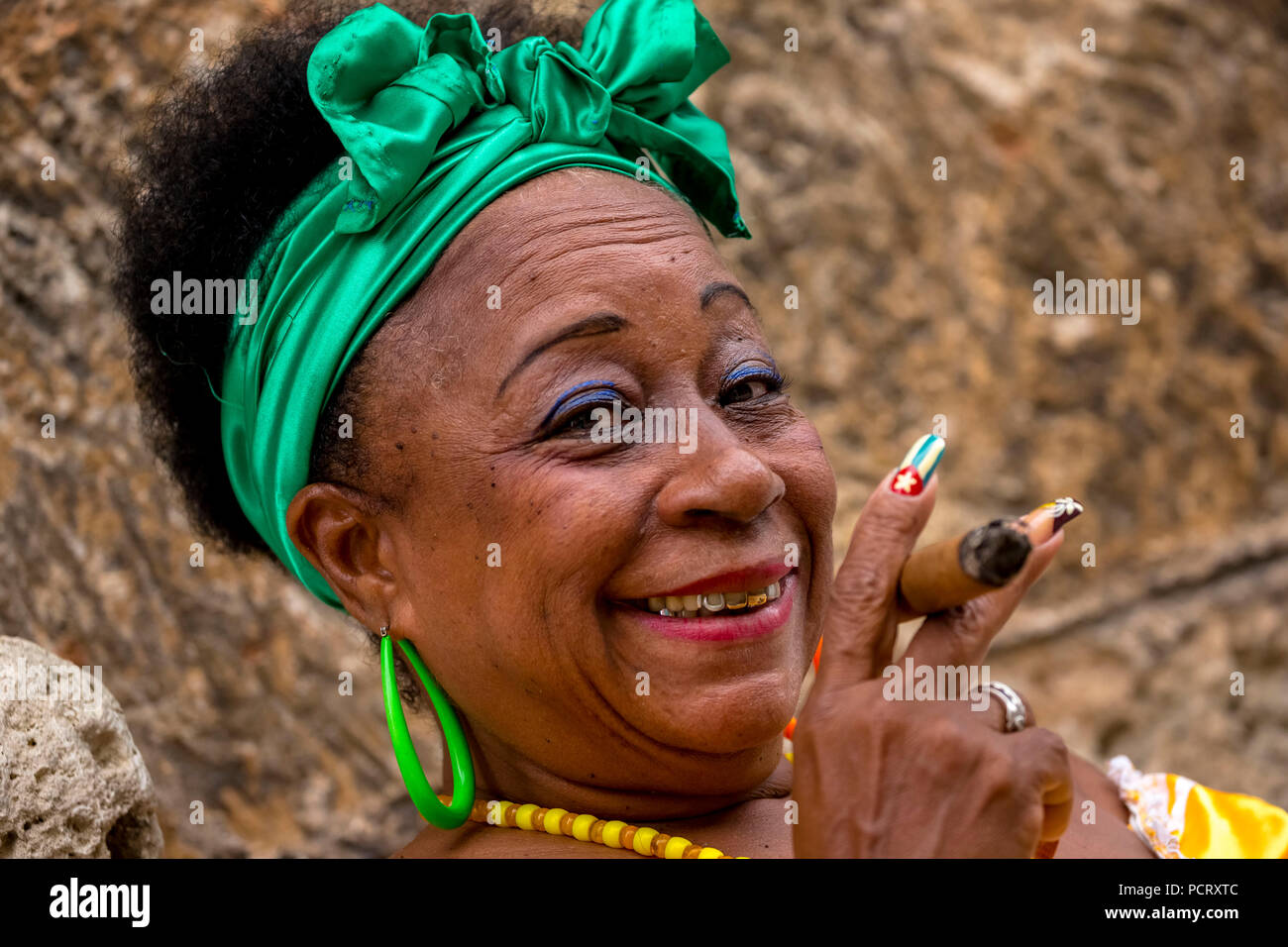 old Cuban woman with green hair ribbon smokes a Havana cigar, Caribbean, Central America, La Habana, Cuba Stock Photo