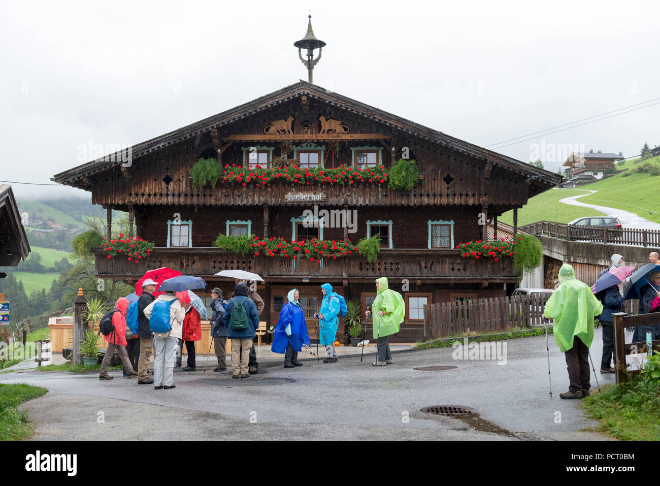 Austria, Alpbach valley, hiker in rainy weather in front of an old farm. Stock Photo
