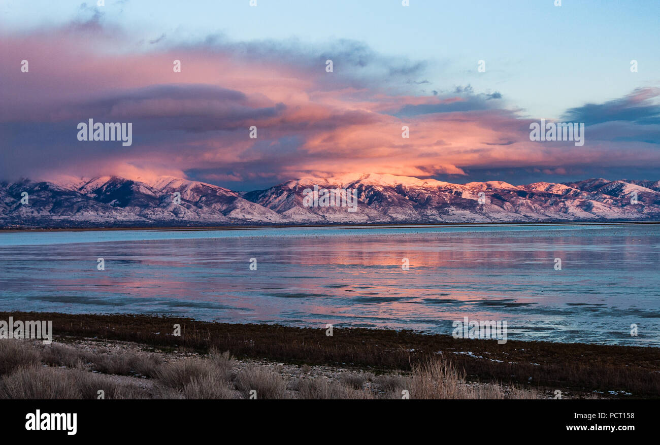 Looking across the Great Salt Lake at the snow covered Wasatch Mountains north of Salt Lake City as the sun sinks low in the sky. Stock Photo