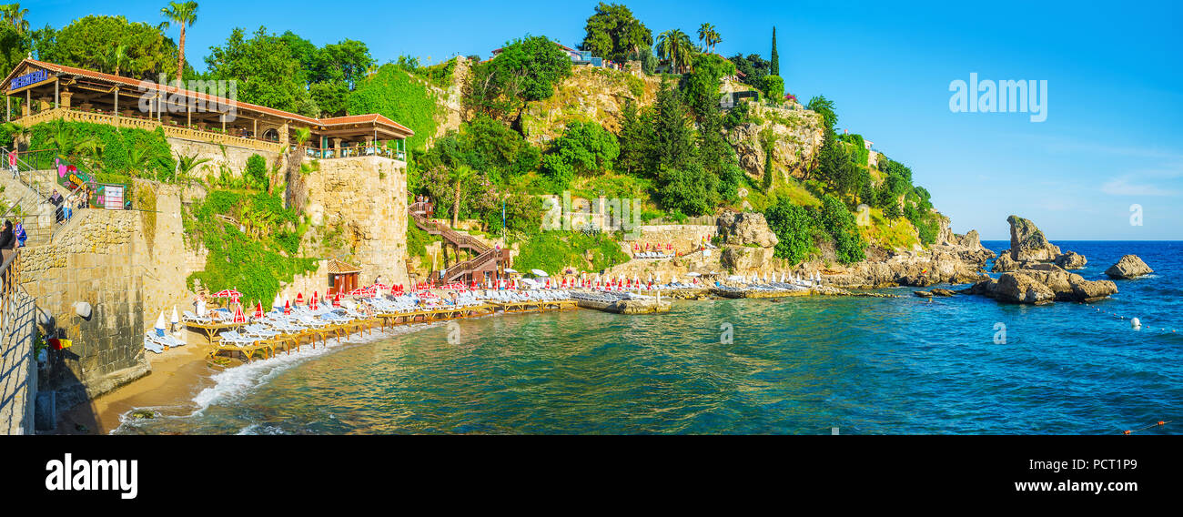 ANTALYA, TURKEY - MAY 11, 2017: The scenic Mermerli beach, stretching along the rocky coast in Kaleici district with tall cliff and green garden on ba Stock Photo