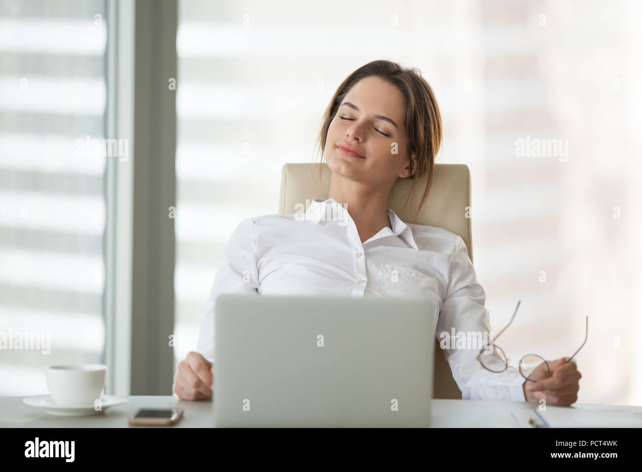 Calm businesswoman leaning in chair with eyes closed Stock Photo