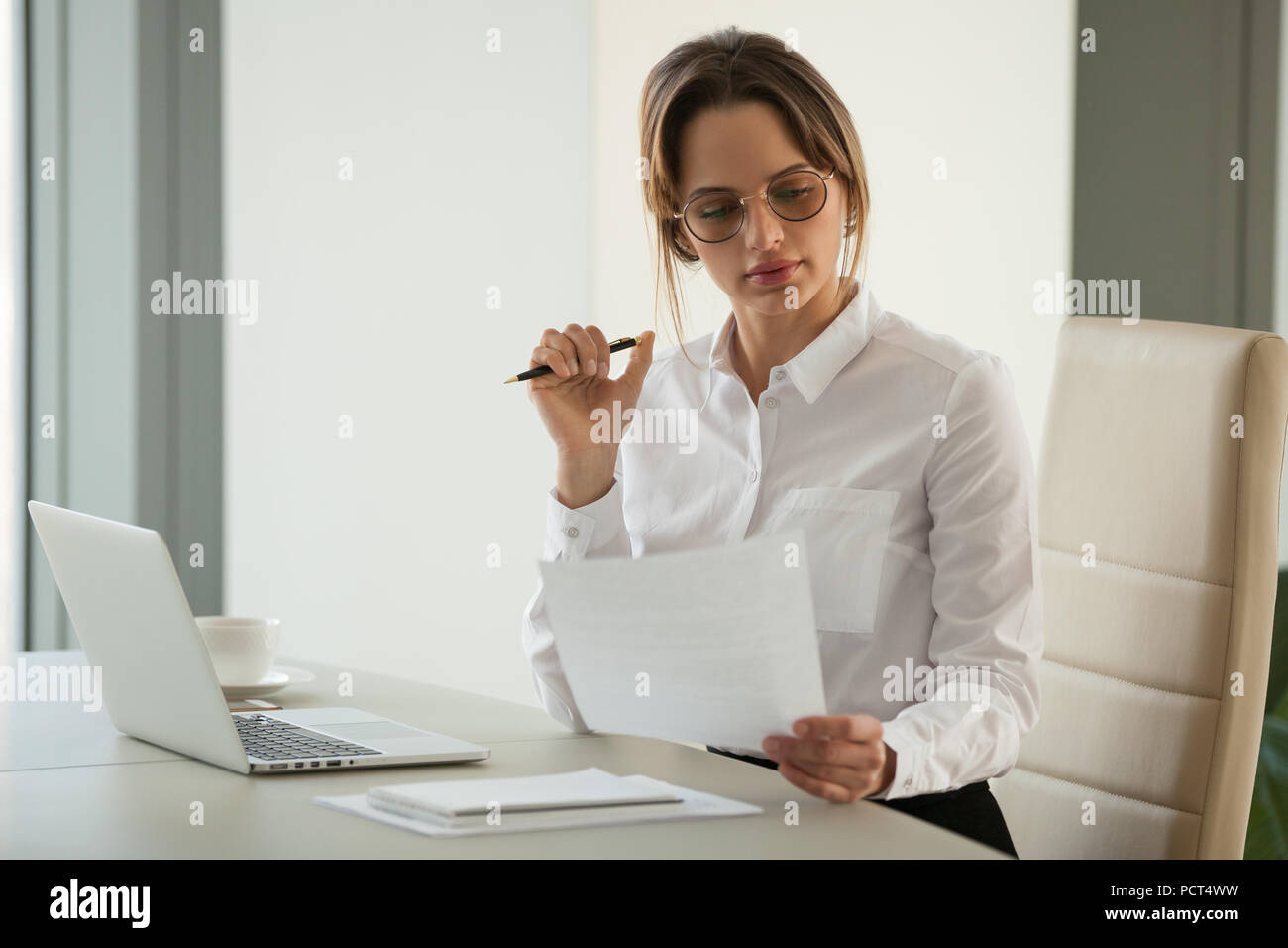 Serious female boss reading document analyzing statistics Stock Photo
