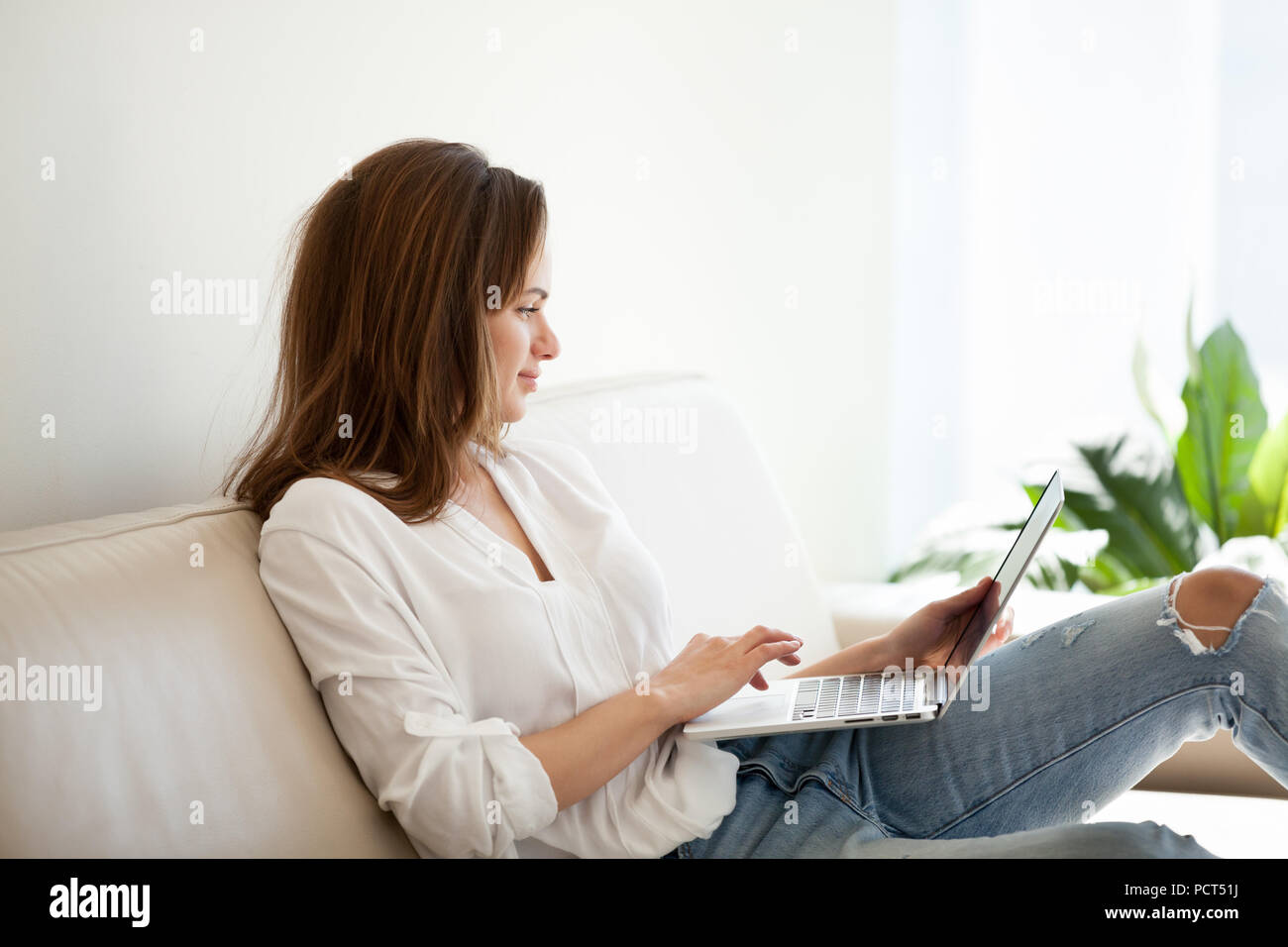 Smiling girl browsing web during weekend at home Stock Photo