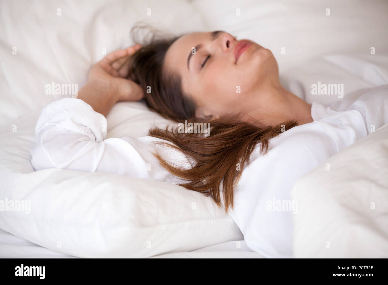 Calm young female sleeping in cozy white bed relaxing Stock Photo