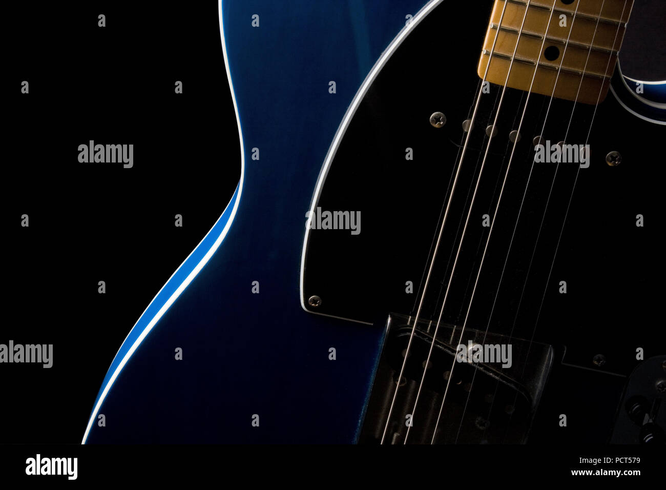 Section of an electric guitar body and neck in close-up with strong side light Stock Photo