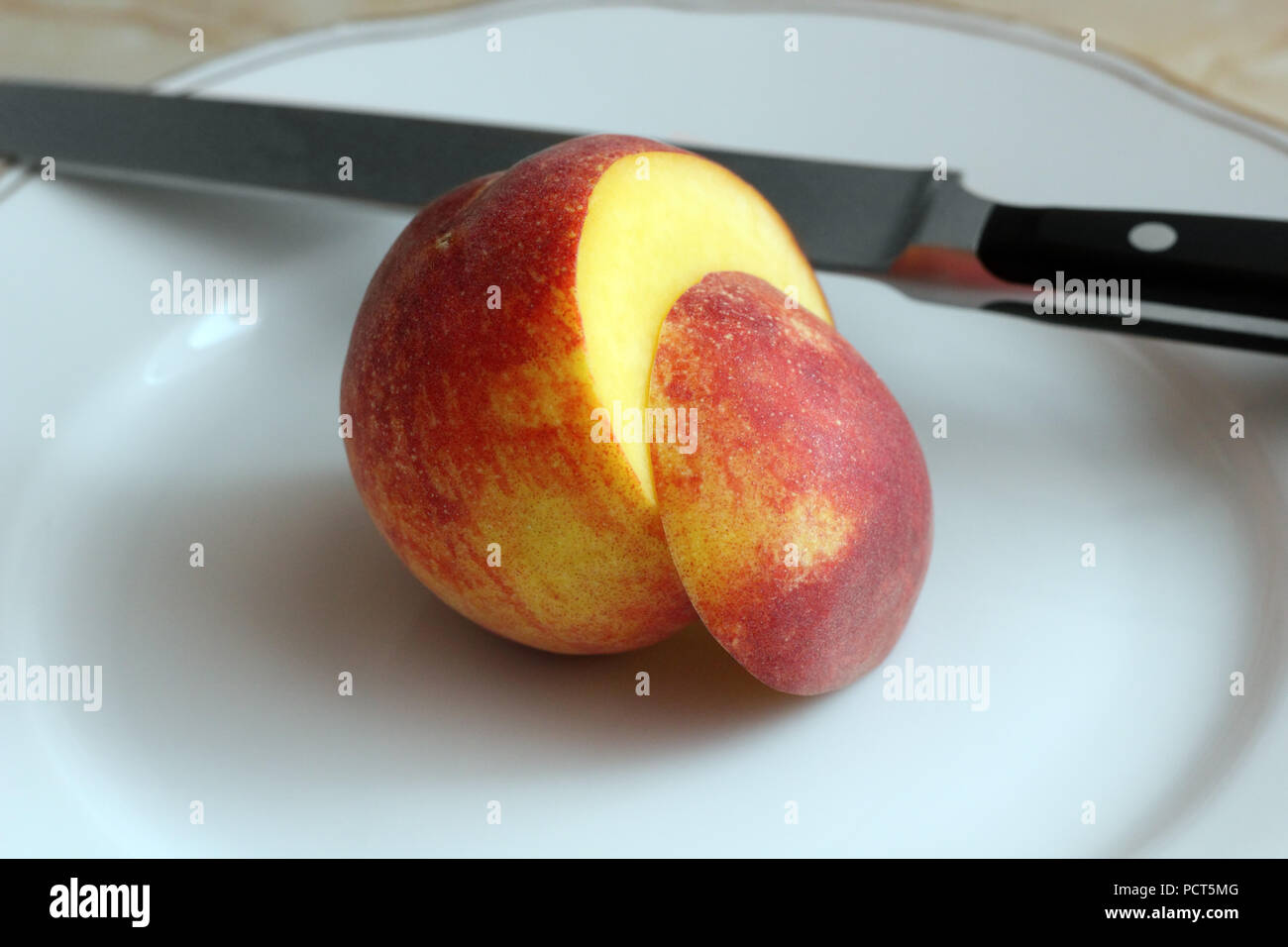 Sliced peach and knife on the white plate photo Stock Photo